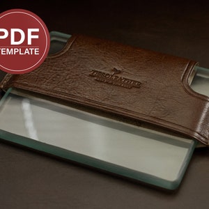 Peut inclure: Un étui en cuir marron avec un insert en verre transparent. L'étui porte le texte "Tissot Leather" en relief sur le devant.