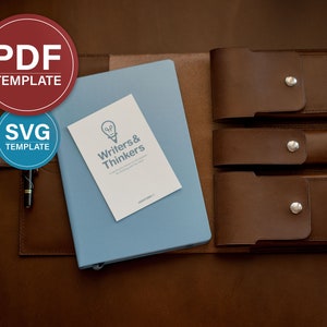 May include: A brown leather notebook cover with three pockets for pens or pencils. The cover is open to reveal a blue notebook with a white card that says "Writers & Thinkers".
