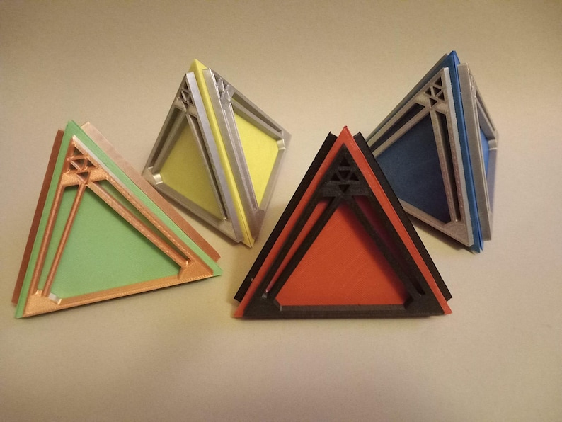 May include: Four triangular shaped boxes made of layered cardboard. The boxes are in different colours: green, yellow, red, and blue. Each box has a decorative design on the front.