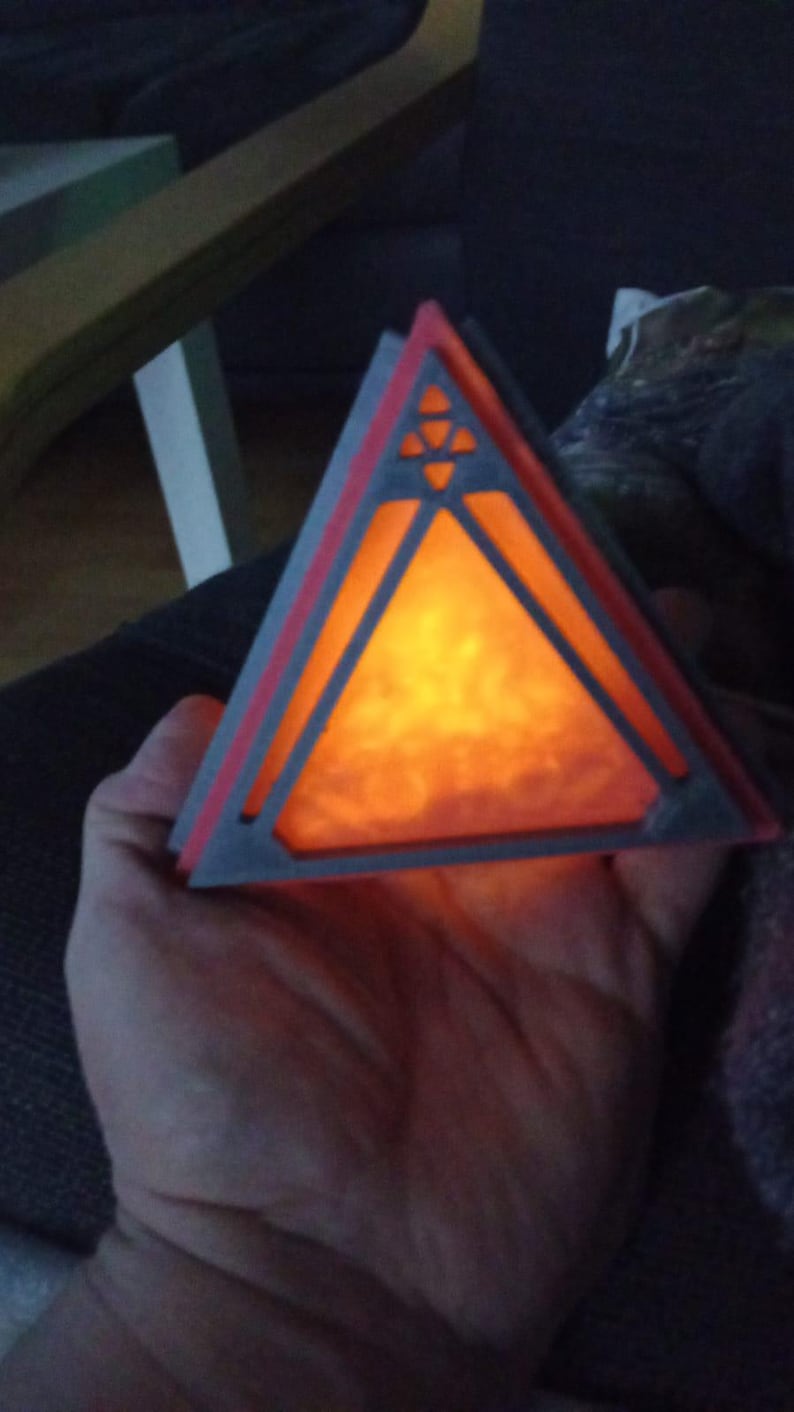 May include: A triangular, 3D printed lamp with a geometric design. The lamp is lit and glows orange.