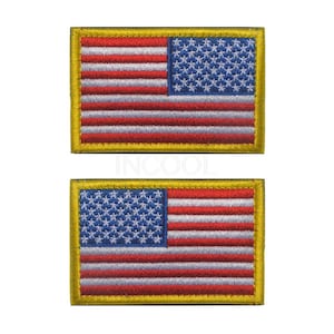 Pu&ograve; includere: Due toppe ricamate della bandiera americana con un bordo dorato. Le toppe sono rettangolari e hanno uno sfondo bianco con strisce rosse e blu e stelle bianche su un campo blu.