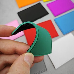 May include: A green silicone patch with black hook and loop fastener. The patch is curved and has a stitched edge. The patch is being held by a hand.