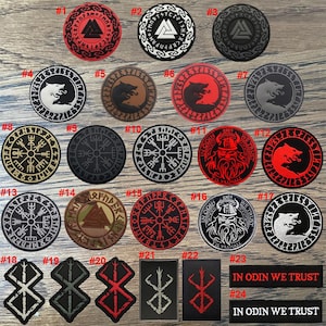 May include: A selection of embroidered patches displaying Viking and Norse symbols. The patches are circular and rectangular, with designs including wolves, compasses, and runes in red, black, white, and brown. Some patches feature the text "IN ODIN WE TRUST".