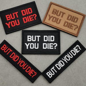 Peut inclure: Cinq patchs en tissu noir et marron avec des broderies blanches et rouges. Les patchs disent tous "But Did You Die?" dans diff&eacute;rents styles de police.