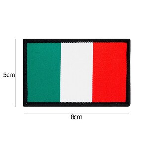 May include: A green, white, and red embroidered patch with a black border. The patch is 5 cm tall and 8 cm wide.