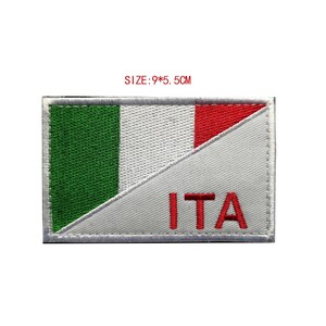 May include: An embroidered patch featuring the Italian flag with the letters "ITA" in red below. The patch is white with a green, white, and red diagonal stripe. The patch measures 9 by 5.5 centimeters.