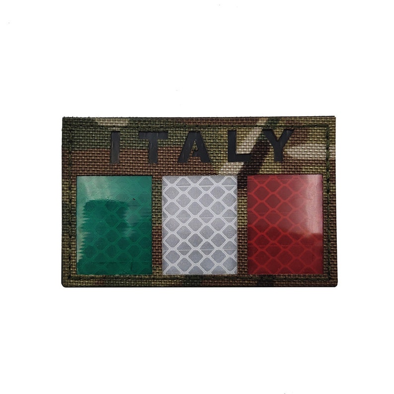 May include: A camouflage fabric patch with the word "ITALY" printed in black letters. The patch features a green, white, and red Italian flag with reflective material.