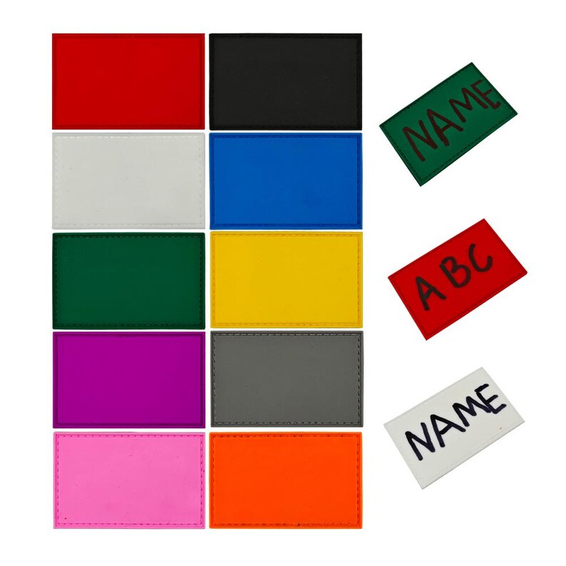 May include: A set of 10 blank iron-on patches in various colours, including red, white, blue, green, yellow, purple, grey, pink, and orange. The patches are all the same size and shape, and they have a stitched border. There are also three iron-on patches with text, one that says "NAME" in green, one that says "NAME" in white, and one that says "ABC" in red.