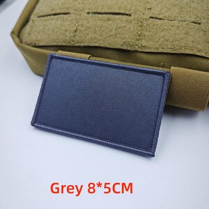 May include: A grey, rectangular patch with a stitched border. The patch is 8 centimetres by 5 centimetres. Grey 8*5CM is written in red below the patch.