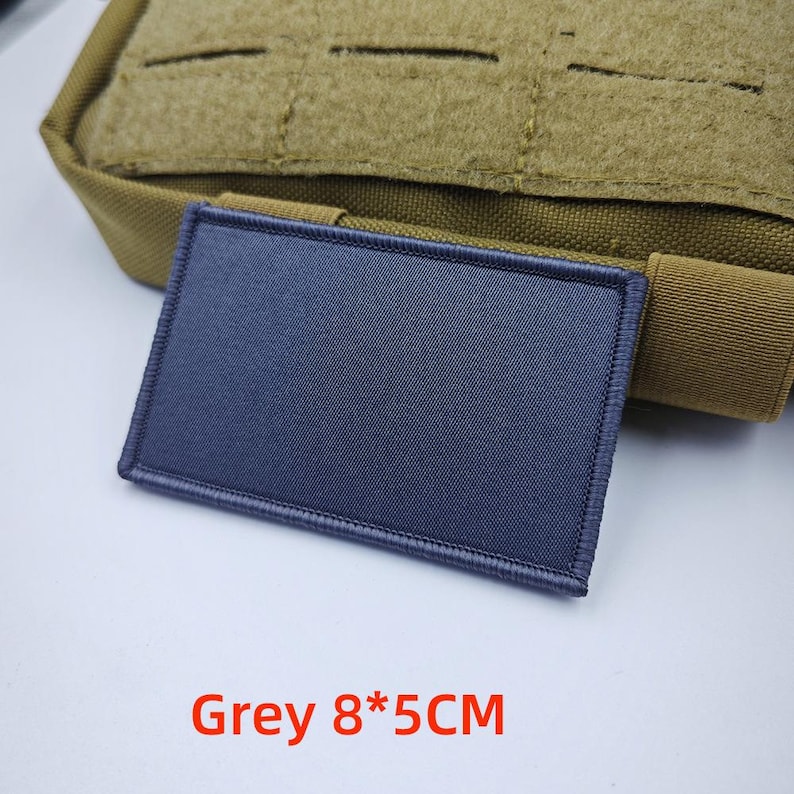 May include: A grey, rectangular patch with a stitched border. The patch is 8 centimetres by 5 centimetres. Grey 8*5CM is written in red below the patch.
