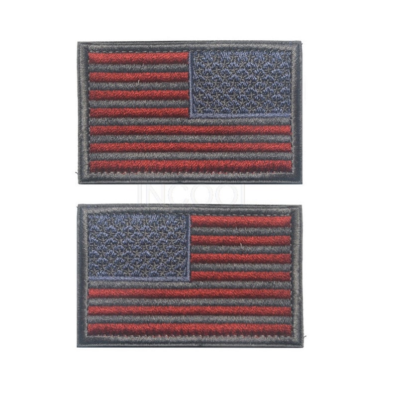 Pu&ograve; includere: Due toppe ricamate della bandiera americana con cuciture rosse e blu su sfondo nero.