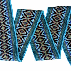 May include: A turquoise blue woven ribbon with a geometric pattern in black, orange, and blue. The ribbon is folded and twisted, showing the pattern from different angles.
