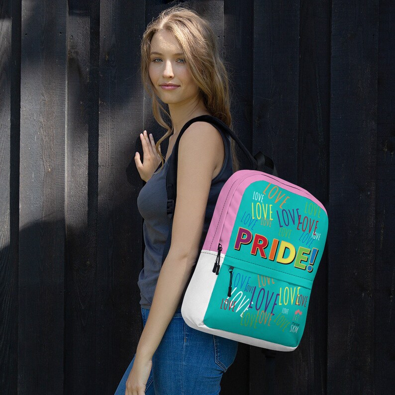 Op de afbeelding: Een turquoise en roze rugzak met de woorden "LOVE" en "PRIDE!" erop gedrukt in regenboogkleuren.