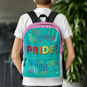 Op de afbeelding: Een turquoise rugzak met een roze rand en een regenboogkleurige "PRIDE!"-afbeelding. De rugzak is bedekt met het woord "LOVE" in verschillende kleuren en maten.