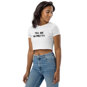 May include: White cropped t-shirt with black text that reads "TELL ME I'M PRETTY."