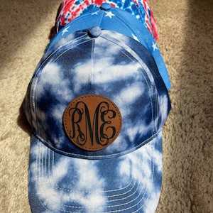 May include: A blue and white tie-dye baseball cap with a brown leather patch that says "RME" in black.