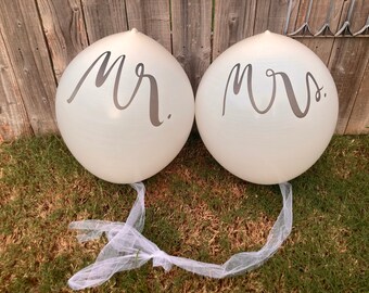 May include: Two white balloons with black lettering. The balloon on the left says "Mr." and the balloon on the right says "Mrs."