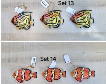May include: Set 13 and Set 14 fish ornaments. Set 13 features three yellow, orange, and black fish ornaments. Set 14 features three red, orange, and white fish ornaments. Each ornament has a gold string for hanging.