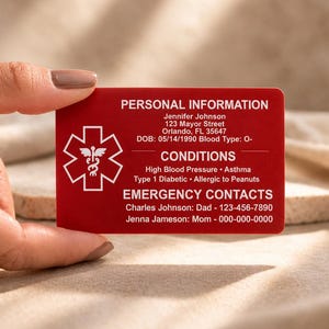 May include: A rectangular red medical identification card featuring a white Star of Life symbol on the left. The card displays printed personal information, medical conditions including asthma and diabetes, and emergency contact details in white text.