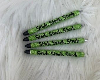 May include: Four green glitter pens with black ink and the text "Stink, Stark, Stunk" printed on them.