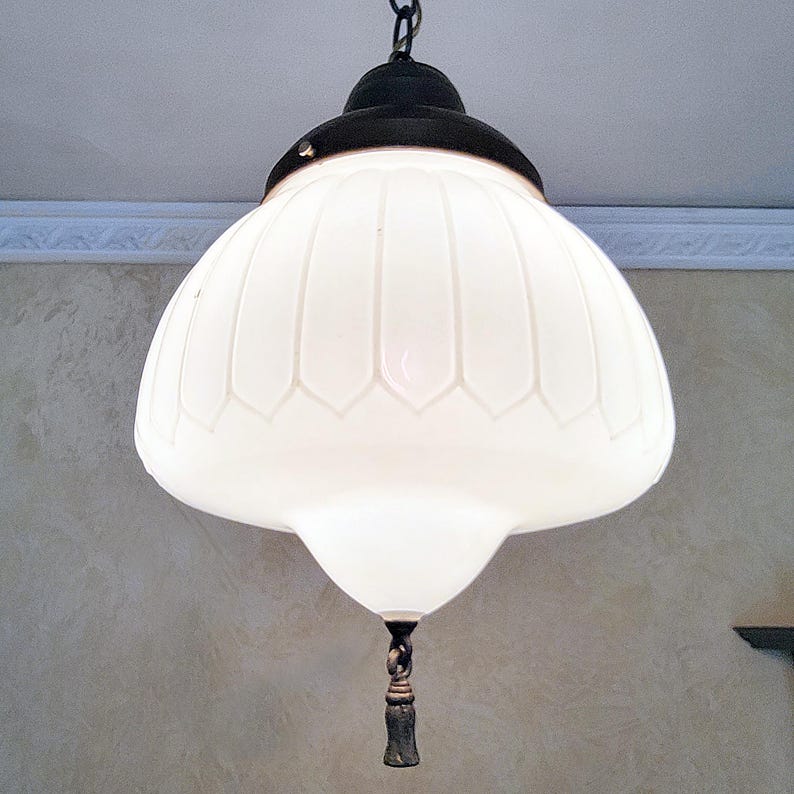 May include: A white glass pendant light fixture with a black metal canopy and a decorative chain. The glass shade has a fluted design and a rounded bottom.