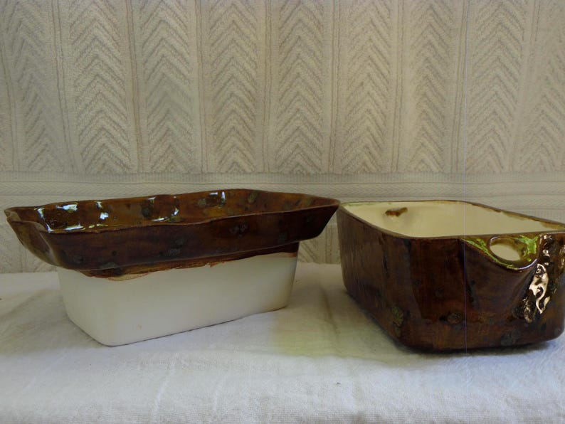 Pu&ograve; includere: Due fioriere rettangolari in ceramica. Una &egrave; marrone con base bianca, l'altra &egrave; marrone con interno color crema. Entrambe hanno una finitura lucida e sono poste su uno sfondo bianco strutturato.