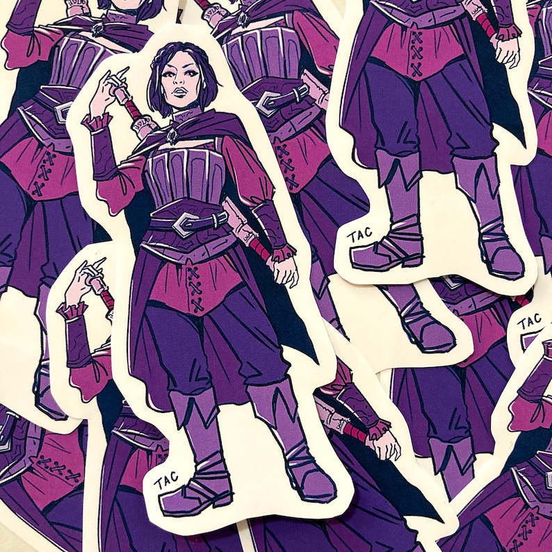Puede incluir: Una pegatina con una ilustraci&oacute;n morada y rosa de un personaje de fantas&iacute;a sosteniendo una espada. El personaje lleva un atuendo morado y rosa con un cintur&oacute;n y una espada. La pegatina tiene la palabra "TAC" impresa en ella.
