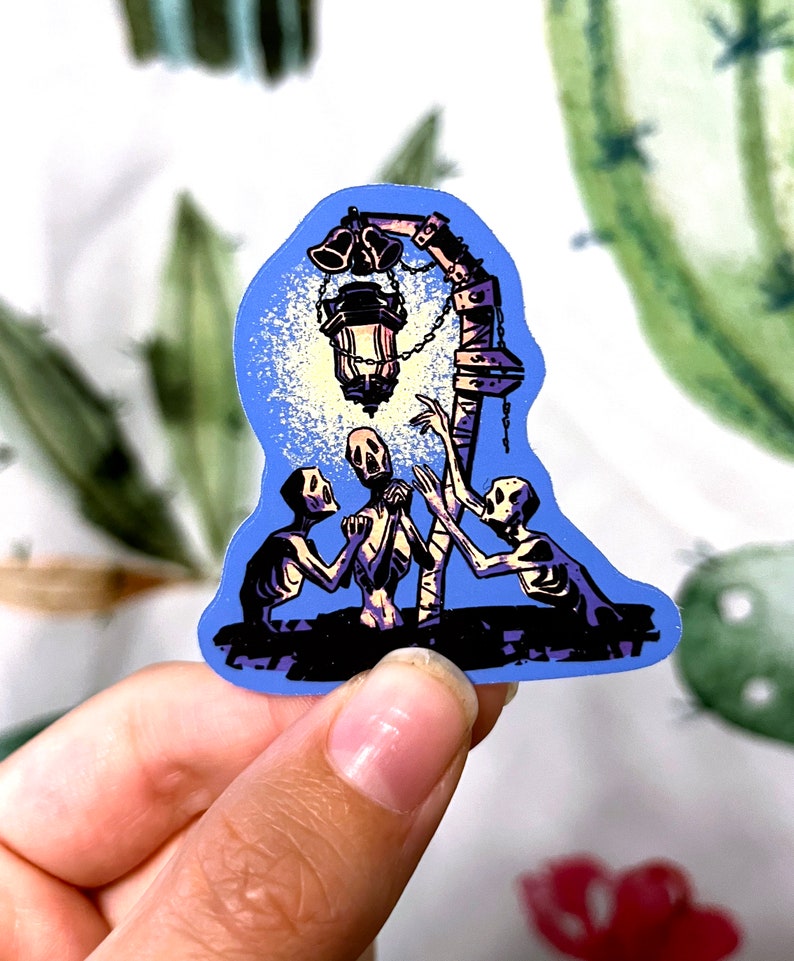 Pu&ograve; includere: Un adesivo con uno sfondo blu con tre figure scheletriche che raggiungono una lanterna luminosa con campane appese.
