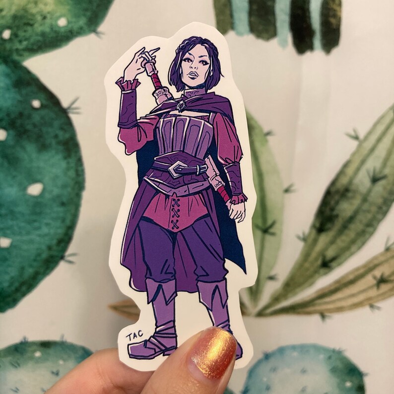 Puede incluir: Una pegatina con una ilustraci&oacute;n de una mujer en un atuendo de fantas&iacute;a, en morado y rojo, sosteniendo una espada. Tiene el pelo oscuro y lleva un vestido morado y rojo con un cintur&oacute;n y una espada. La pegatina tiene un fondo blanco y el texto "TAC" en la esquina inferior izquierda.