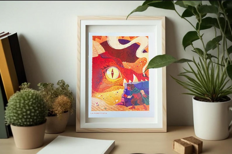 Pu&ograve; includere: Una stampa incorniciata di un'illustrazione colorata che presenta un grande occhio rosso con una pupilla gialla, un drago bianco e arancione e una piccola figura vestita di blu in piedi di fronte al drago. La stampa &egrave; intitolata "La Fortuna".