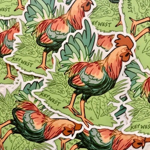 May include: A collection of stickers featuring a rooster illustration. The roosters are depicted in shades of orange, red, and green, with the text "KEY WEST" on a green background. The stickers are suitable for decorating various items.
