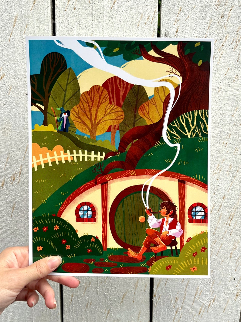 Op de afbeelding: Een kleurrijke illustratie van een hobbit die op een stoel zit voor een ronde deur, terwijl hij een pijp rookt. De hobbit draagt een bruin shirt en broek en heeft bruin haar. De deur is groen en heeft een rond raam. De achtergrond is een groene heuvel met een wit hek en bomen.