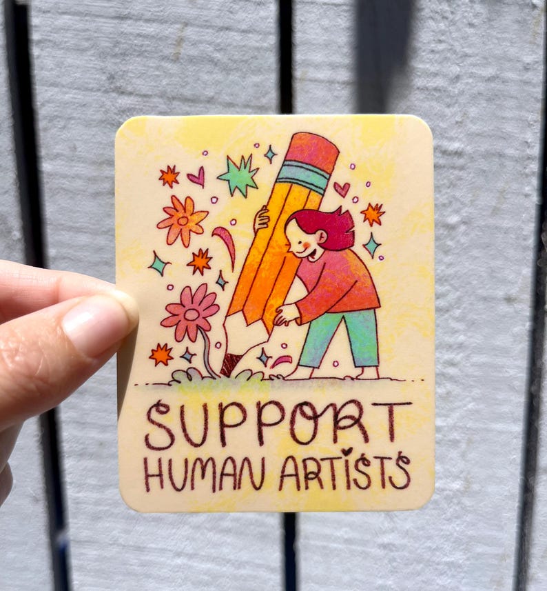 May include: A yellow and orange pencil is being planted in the ground by a person with red hair. The pencil is surrounded by flowers and stars. The text "SUPPORT HUMAN ARTISTS" is written below the image.