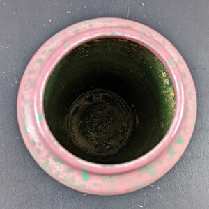 Może przedstawiać: R&oacute;żowa doniczka ceramiczna z zieloną glazurą w środku. Doniczka ma nakrapianą powierzchnię i jest pusta.