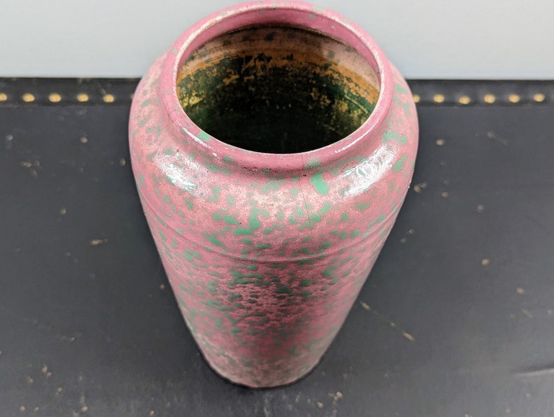 Może przedstawiać: R&oacute;żowy ceramiczny wazon z zielonymi plamkami. Wazon ma okrągły otw&oacute;r i cylindryczny kształt.
