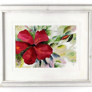 Può includere: Un dipinto ad acquerello incorniciato di un fiore di ibisco rosso con foglie verdi e sfondo bianco.