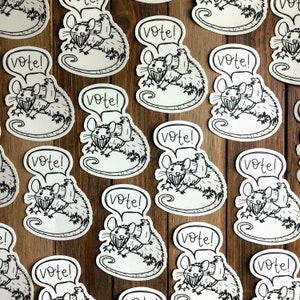 May include: A set of 12 black and white stickers featuring a cartoon rat holding a sign that says "Vote!" The rat is wearing a hat and has a big smile. The stickers are perfect for adding a touch of humor to your laptop, water bottle, or notebook.
