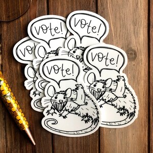 May include: Five white stickers with black line drawings of rats and the word "Vote!" in a speech bubble. The rats have large teeth and are drawn in a cartoon style.