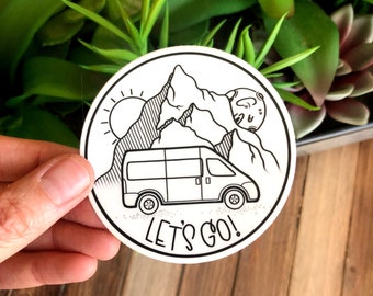 May include: Black and white sticker featuring a van driving through a mountain landscape with a sun and moon in the background. The text "LET'S GO!" is printed below the van.