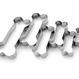 May include: Set of five stainless steel bone-shaped cookie cutters of varying sizes.