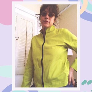 May include: A bright green zip-up jacket with a black zipper and a high collar.