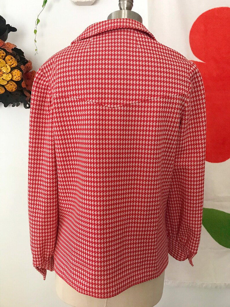 May include: A red and white gingham button-up shirt with long sleeves and a collared neckline.