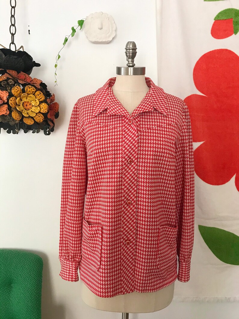 May include: A red and white gingham button-up shirt with long sleeves and two patch pockets. The shirt is on a white mannequin.