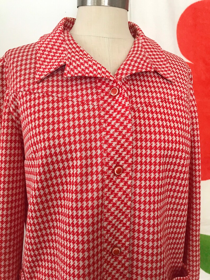 May include: A red and white houndstooth patterned jacket with a button-up front.