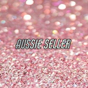 Może przedstawiać: R&oacute;żowe błyszczące tło z tekstem "Aussie Seller" w srebrnej, obwiedzionej czcionce.