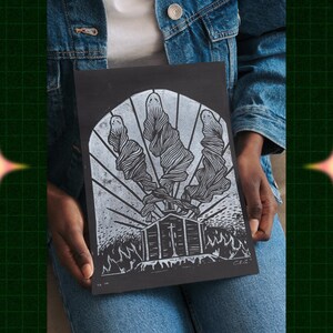 Puede incluir: Una impresión de linóleo en blanco y negro que representa tres figuras estilizadas, que parecen fantasmas o espíritus, con una pequeña iglesia en el fondo. La iglesia tiene una cruz en el techo y está situada sobre un fondo de llamas. La impresión está en papel negro con un borde blanco.