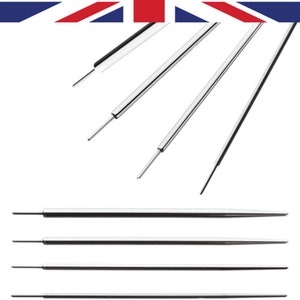 May include: A set of six silver sewing needles with black tips. The needles are arranged in a row, with the tips pointing to the right.