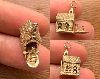 Op de afbeelding: Gouden bedel in de vorm van een kerk met een stel erin. De kerkdeur staat open en het stel houdt elkaars hand vast. De bedel is gedetailleerd met ramen en een toren.