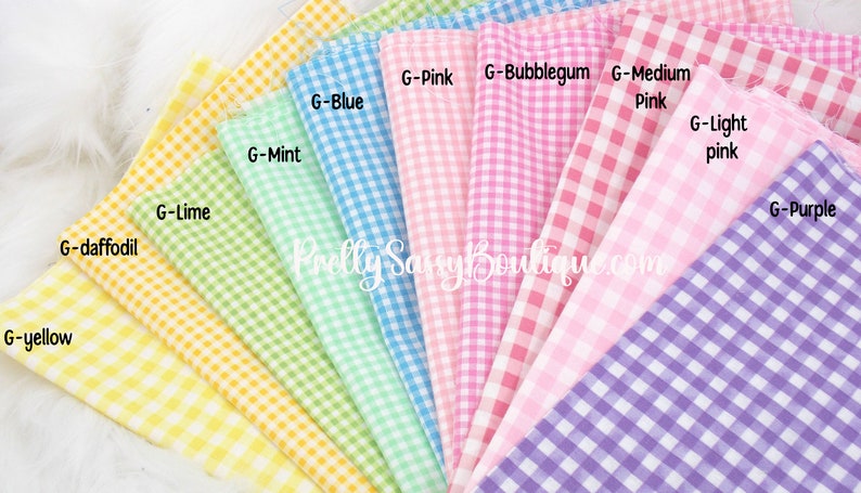 K&ouml;nnte beinhalten: Eine Sammlung von zehn Gingham-Stoffmustern in verschiedenen Pastellfarben, darunter Gelb, Limettengr&uuml;n, Mintgr&uuml;n, Blau, Rosa, Bubblegum-Rosa, Mittelrosa, Hellrosa und Lila. Die Muster sind f&auml;cherf&ouml;rmig angeordnet und mit ihren Farbnamen beschriftet.