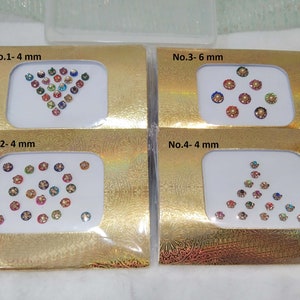 Puede incluir: Cuatro paquetes de pegatinas bindi de colores, adhesivas y con joyas. Cada paquete tiene un diseño y un tamaño diferentes. Los paquetes están etiquetados con los números 1-4 y el tamaño de las pegatinas bindi en milímetros.